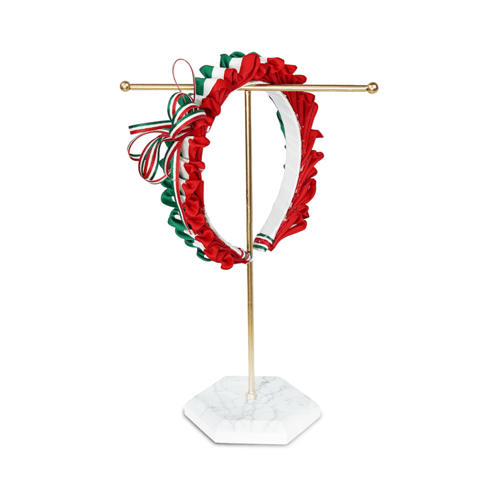 Animación de una diadema decorada con pétalos de listón tricolor verde, blanco y rojo, exhibida en un soporte dorado